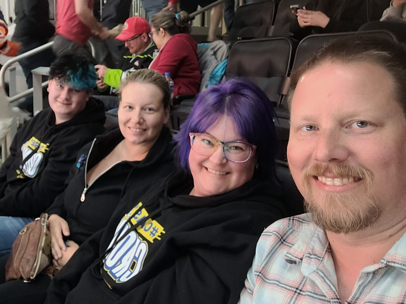 A group of people are sitting in a stadium and smiling for the camera.