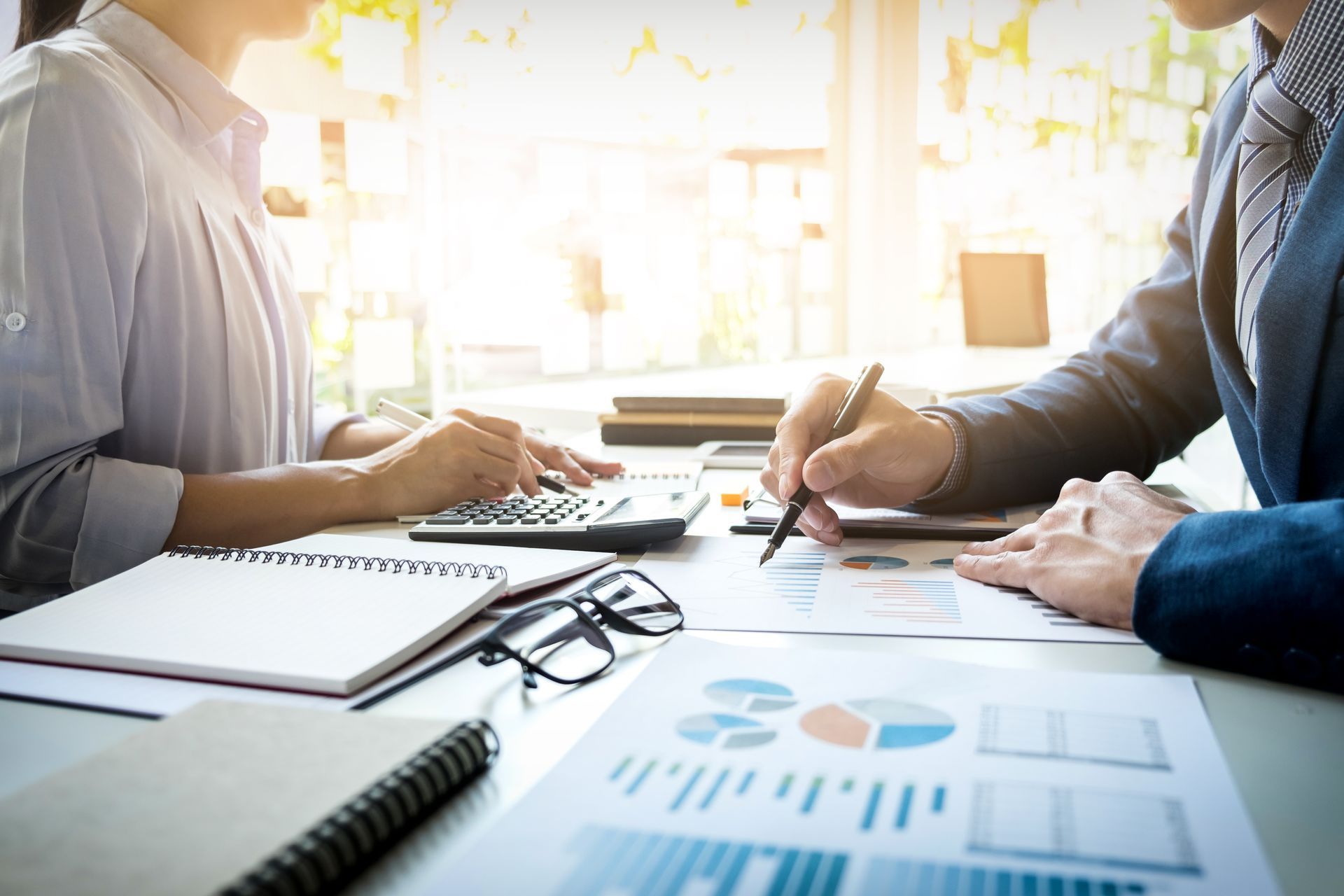A man and a woman are sitting at a table with papers and a calculator.