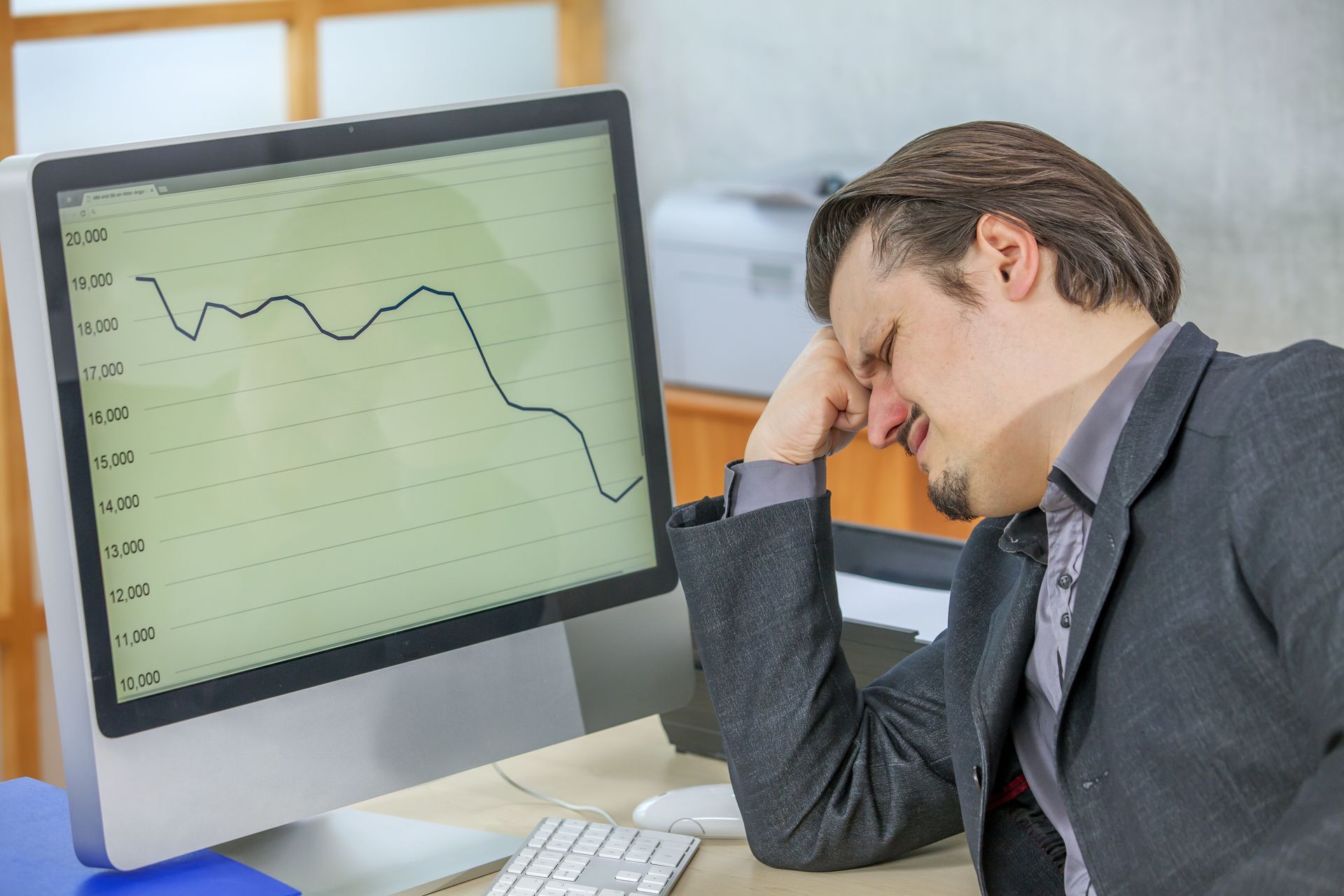 A man is sitting in front of a computer with a graph on it.
