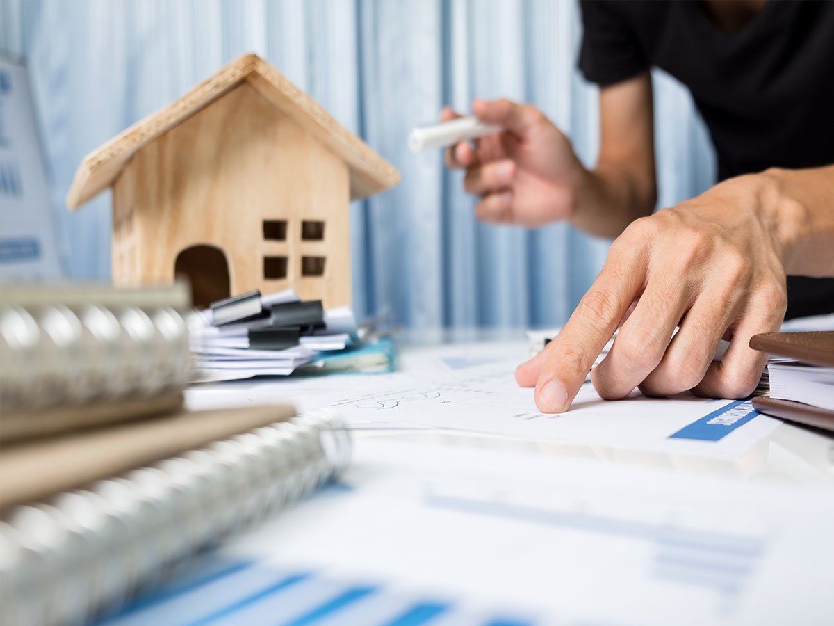 A person is sitting at a table with a model house in the background.