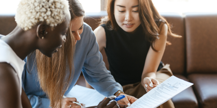 A group of people are sitting on a couch looking at a piece of paper.
