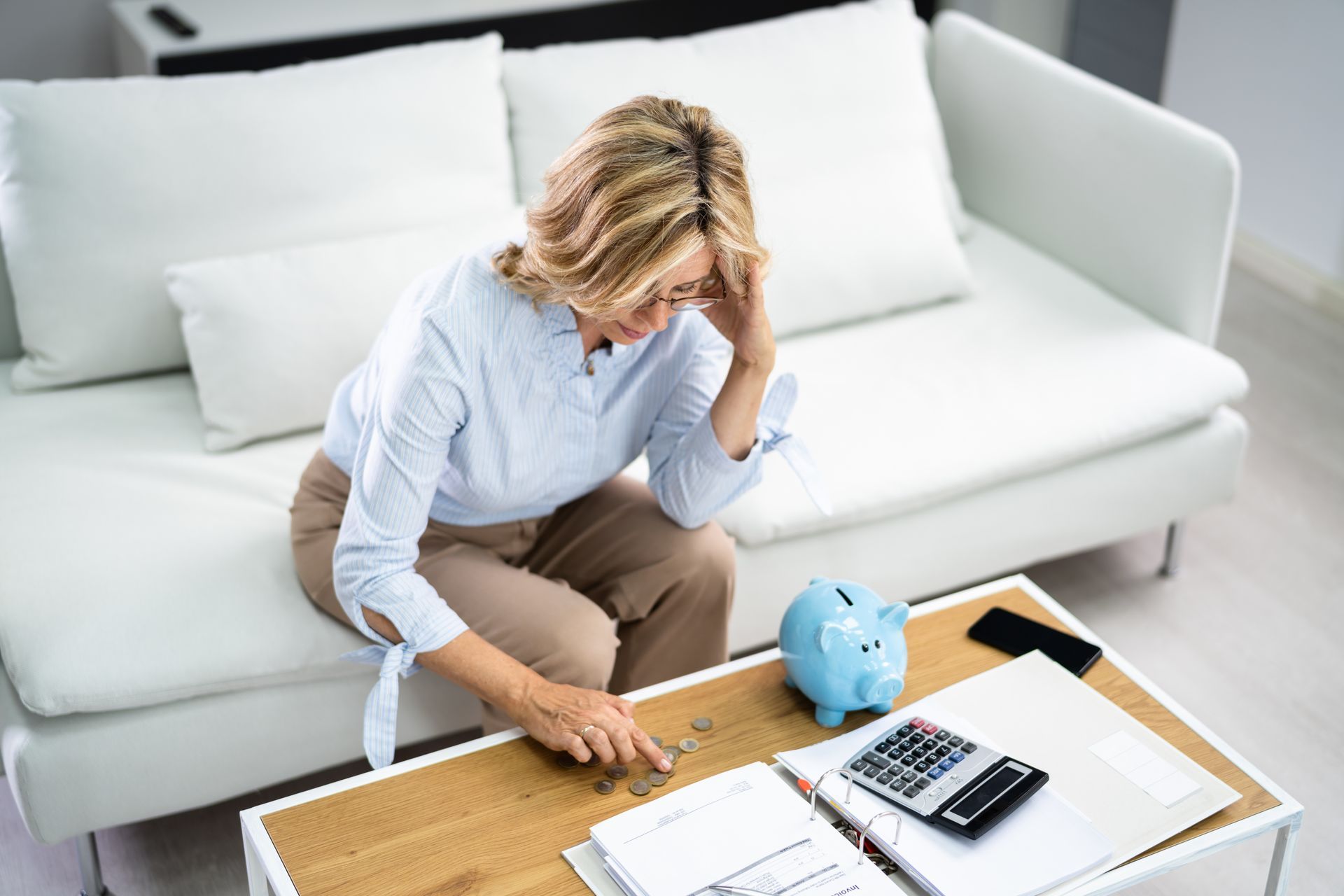A woman is sitting on a couch looking at her finances.