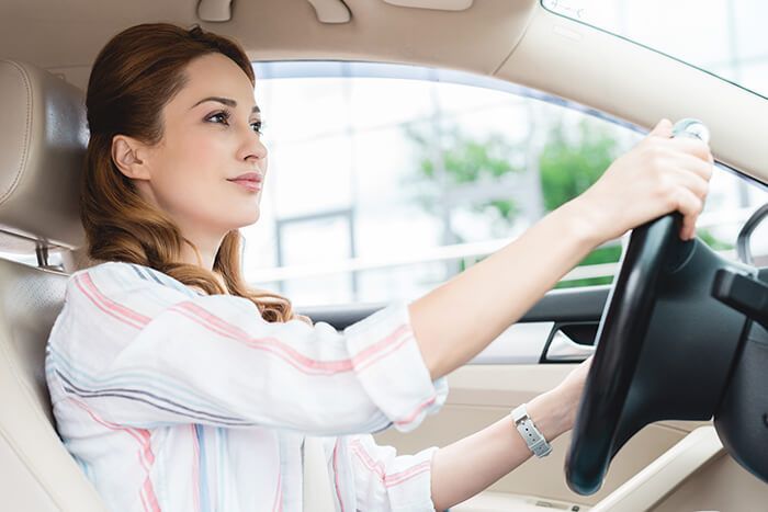 A woman is driving a car and holding the steering wheel.