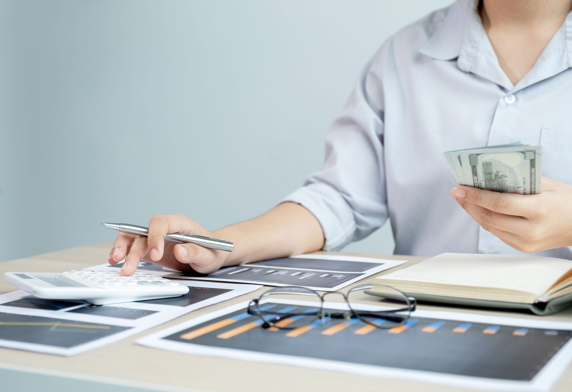 A woman is sitting at a table holding a pen and a calculator.