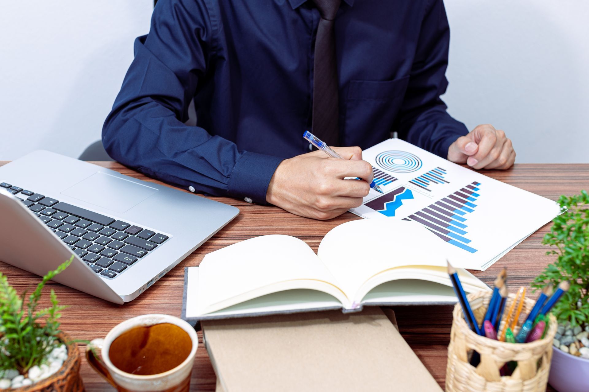 A man is sitting at a desk with a laptop and a notebook.