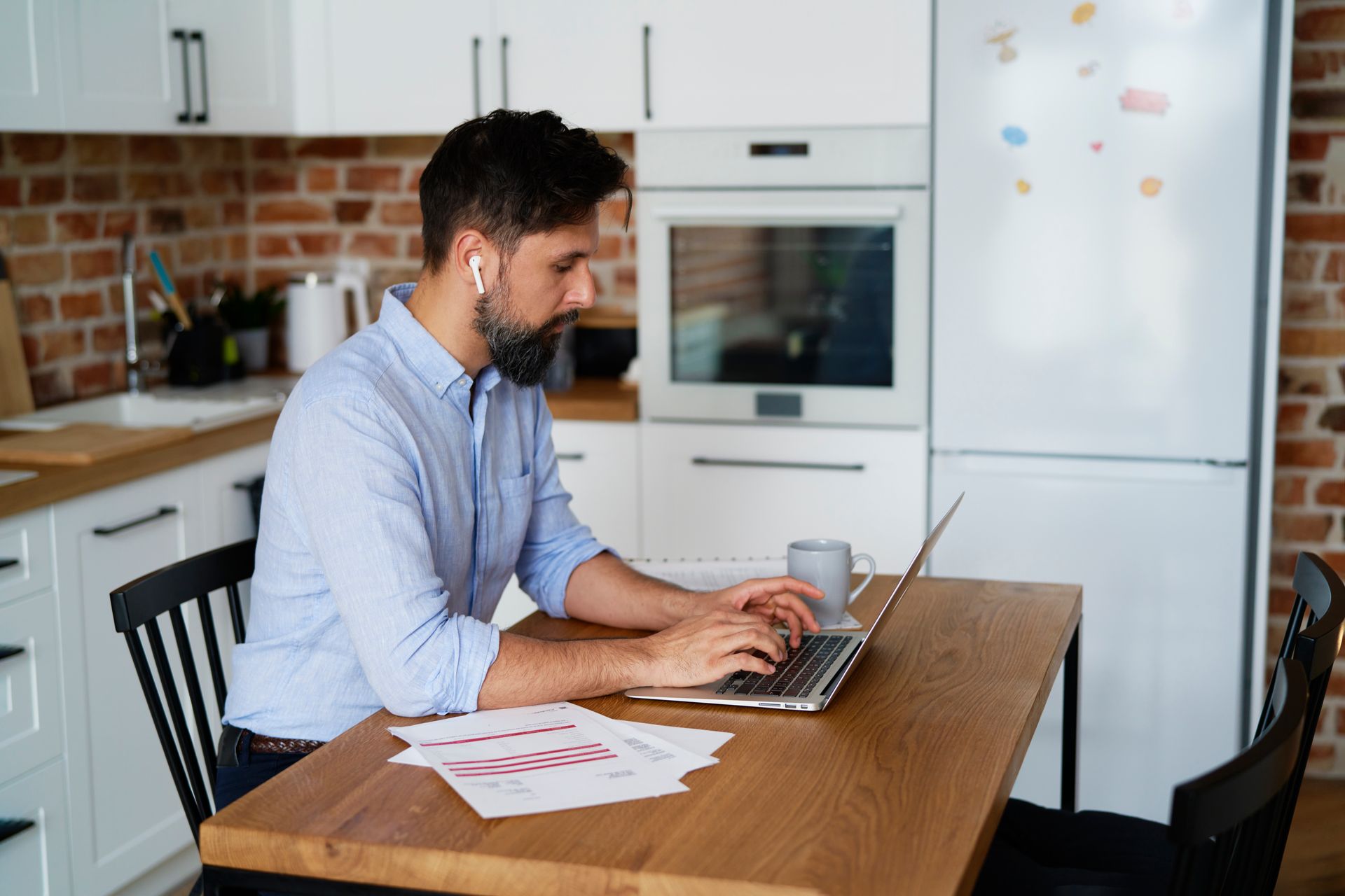 A man is sitting at a table using a laptop computer.
