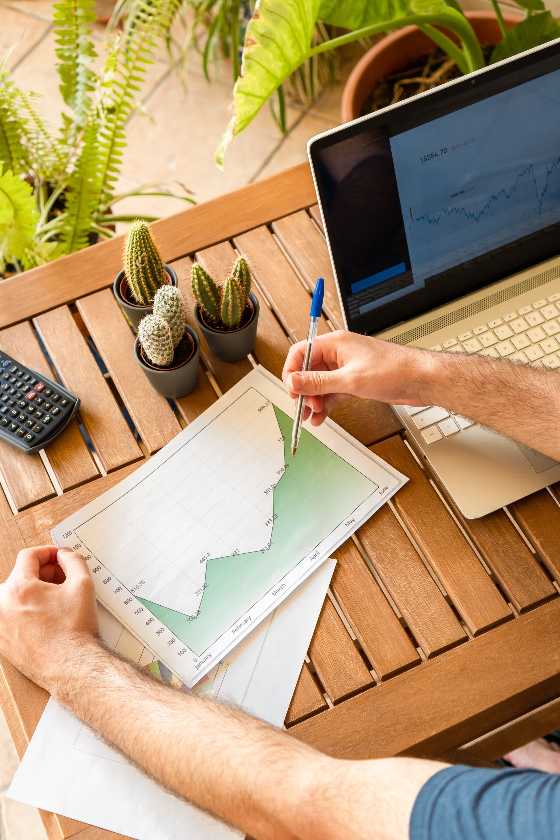 A man is sitting at a table with a laptop and a graph.