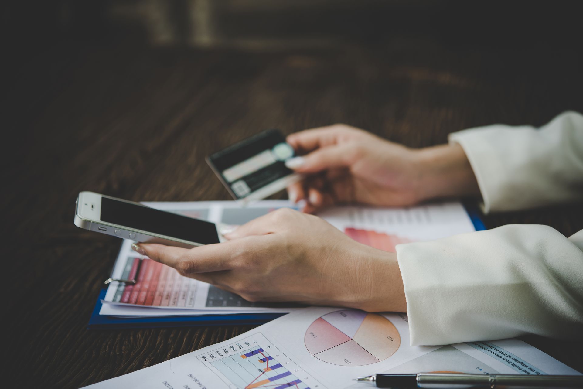 A woman is holding a credit card and a cell phone.