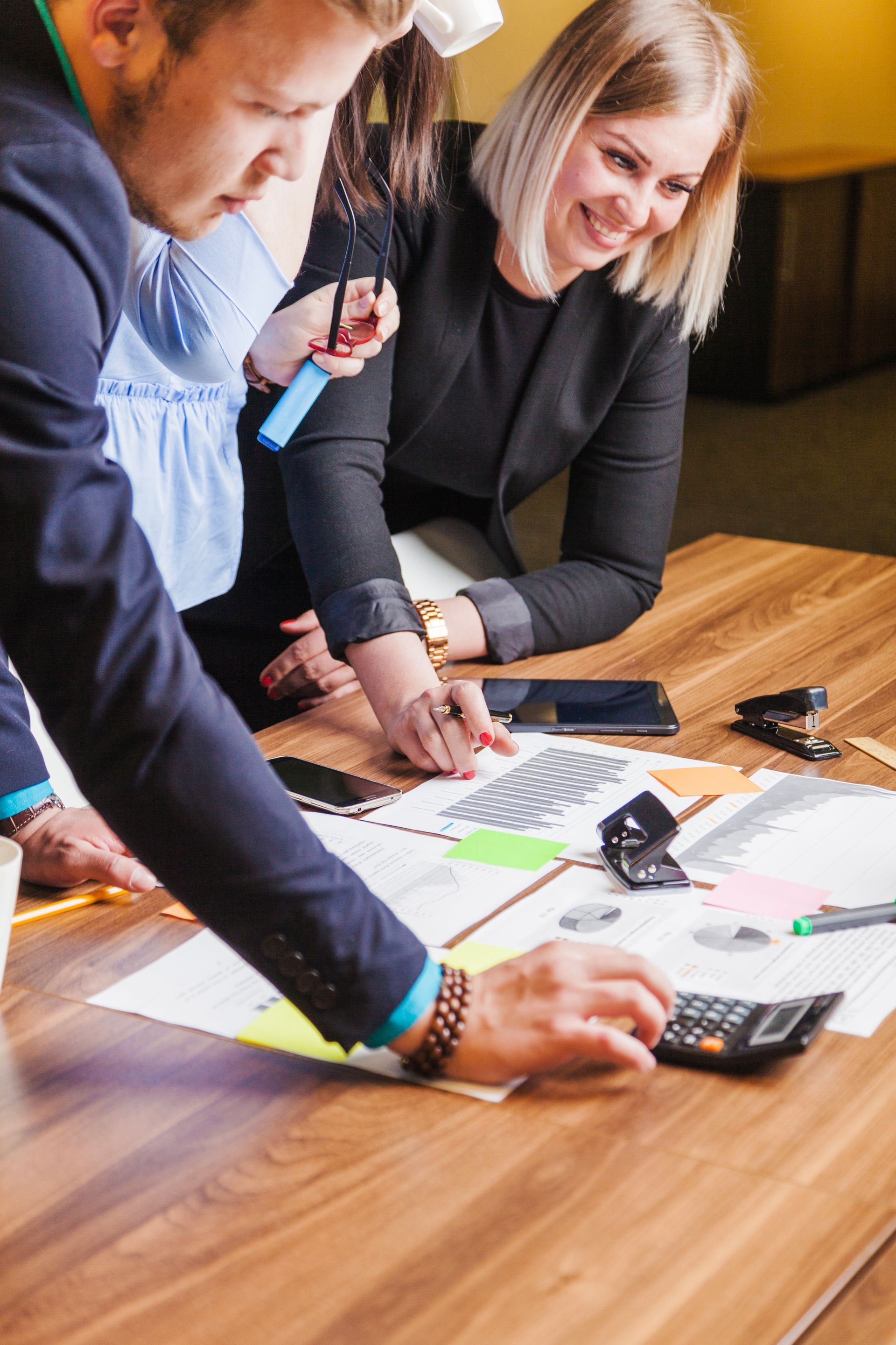 A group of people are sitting at a table with papers and a calculator.