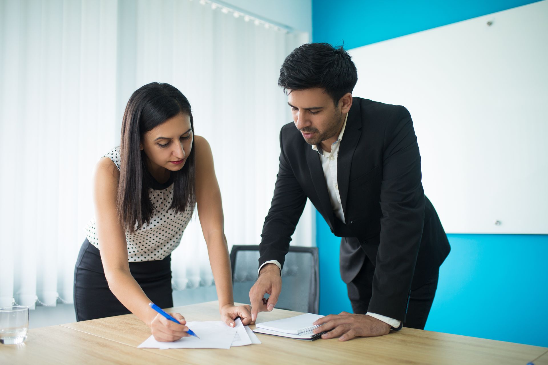 A man and a woman are looking at a piece of paper on a table.
