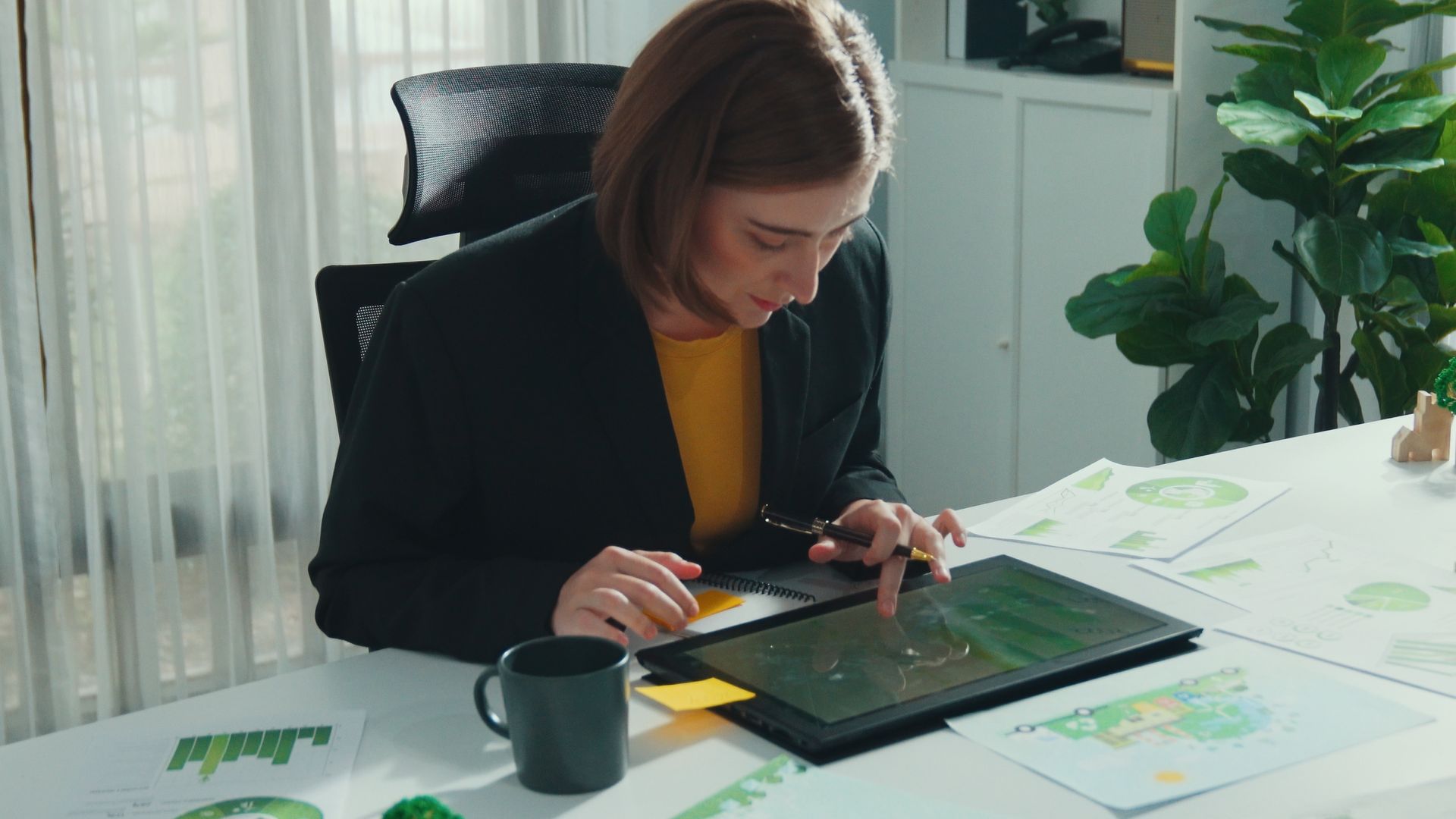 A woman is sitting at a table using a tablet computer.
