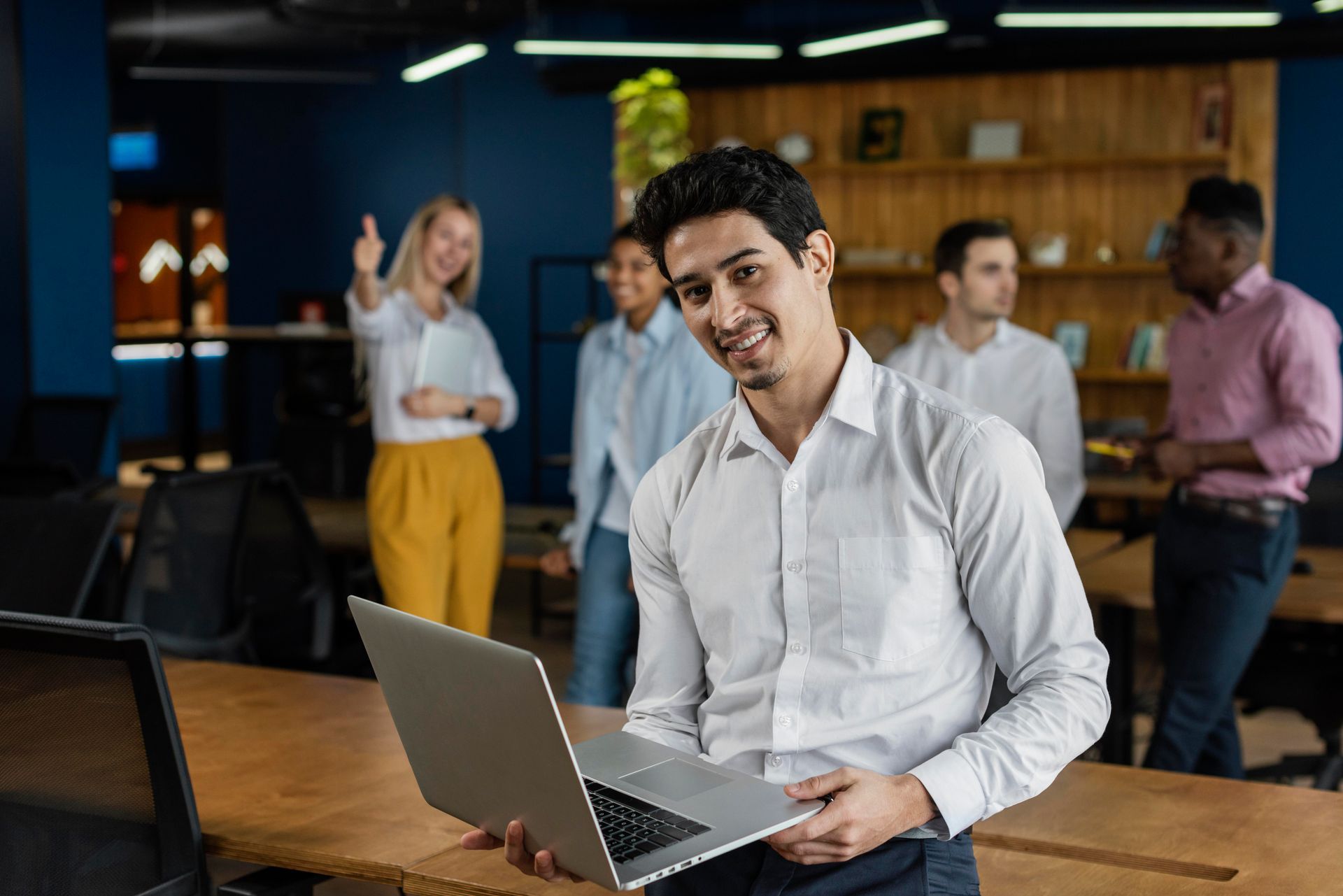 A man is holding a laptop computer in front of a group of people.
