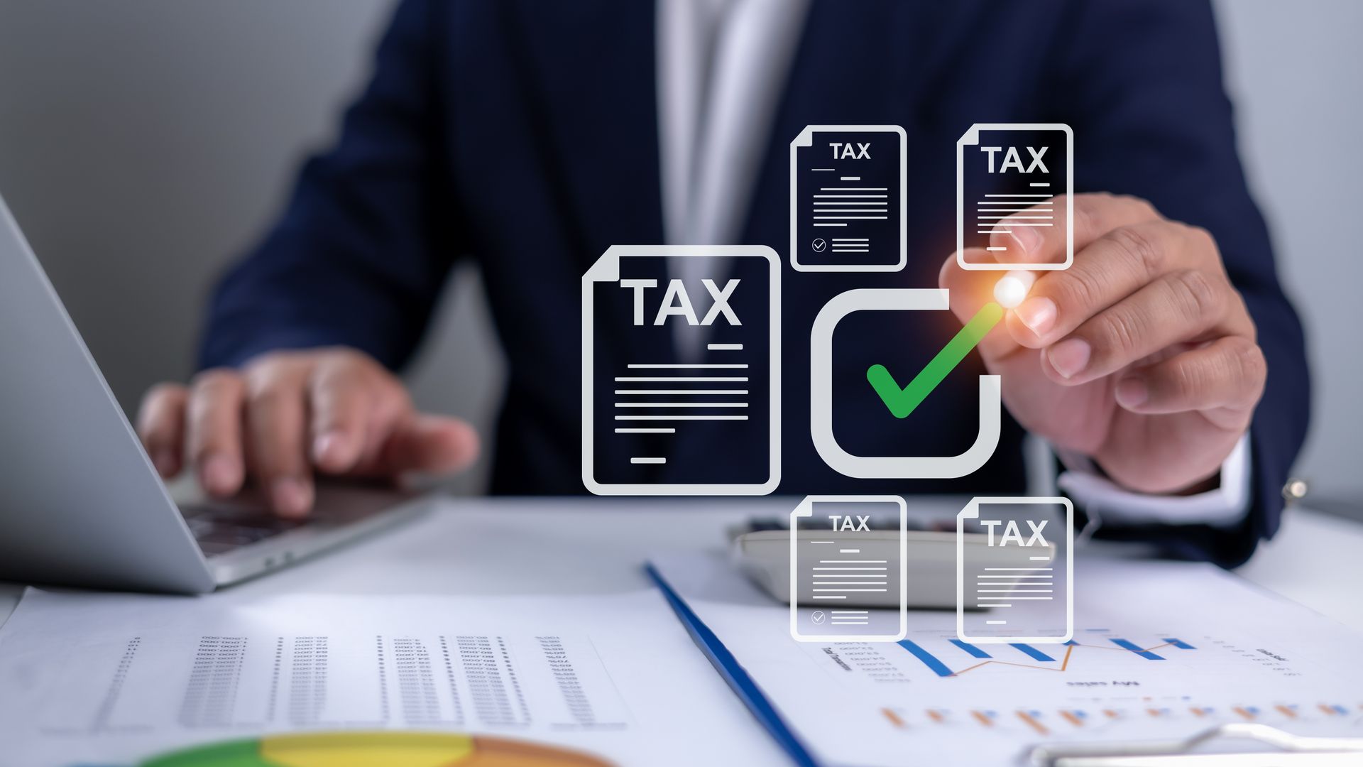 Person reviewing tax documents on a laptop with digital tax icons and a green checkmark on screen
