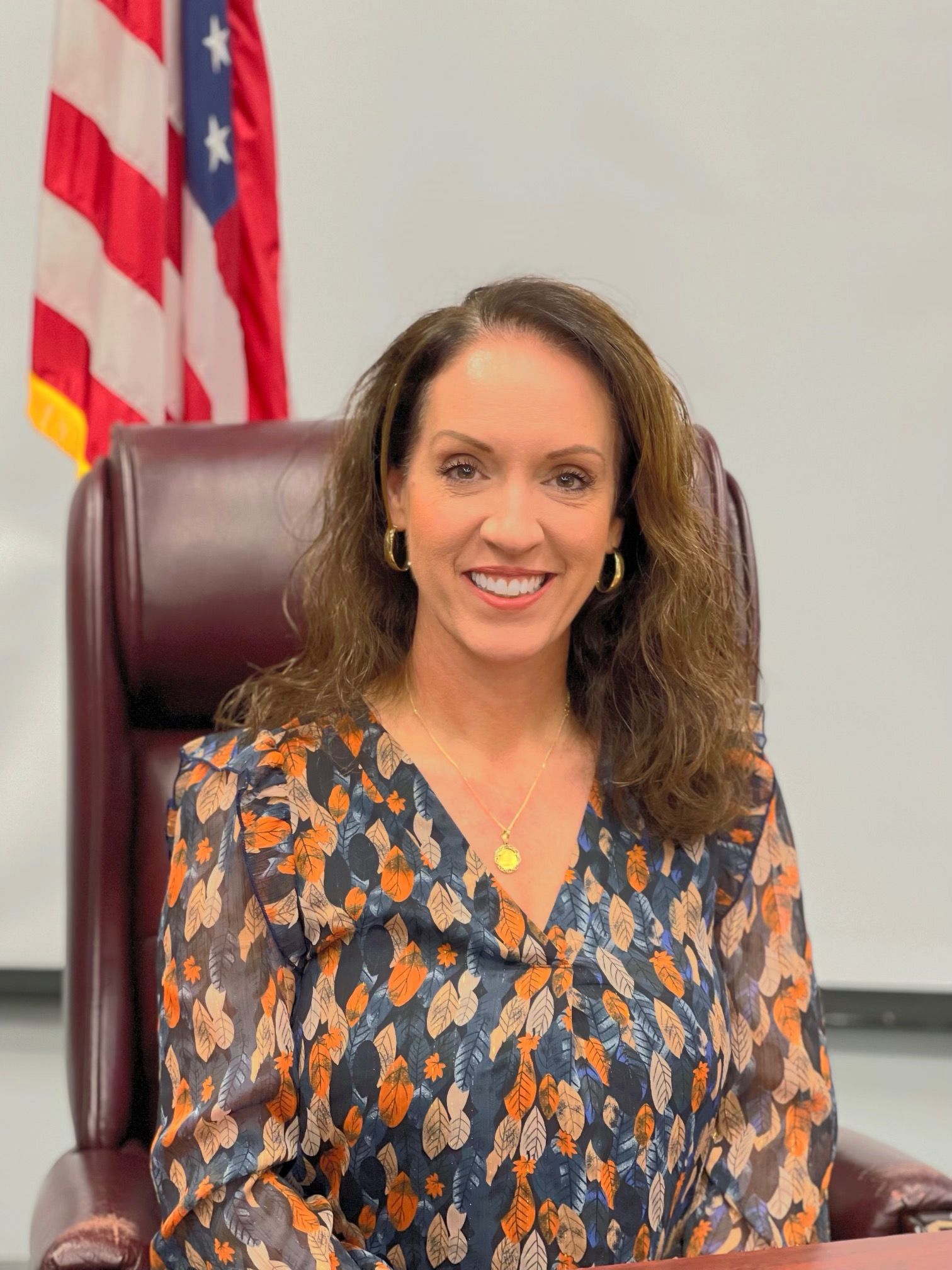 a woman is sitting in a chair in front of an american flag .