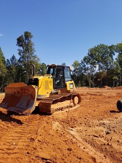 A yellow bulldozer is driving through a dirt field.