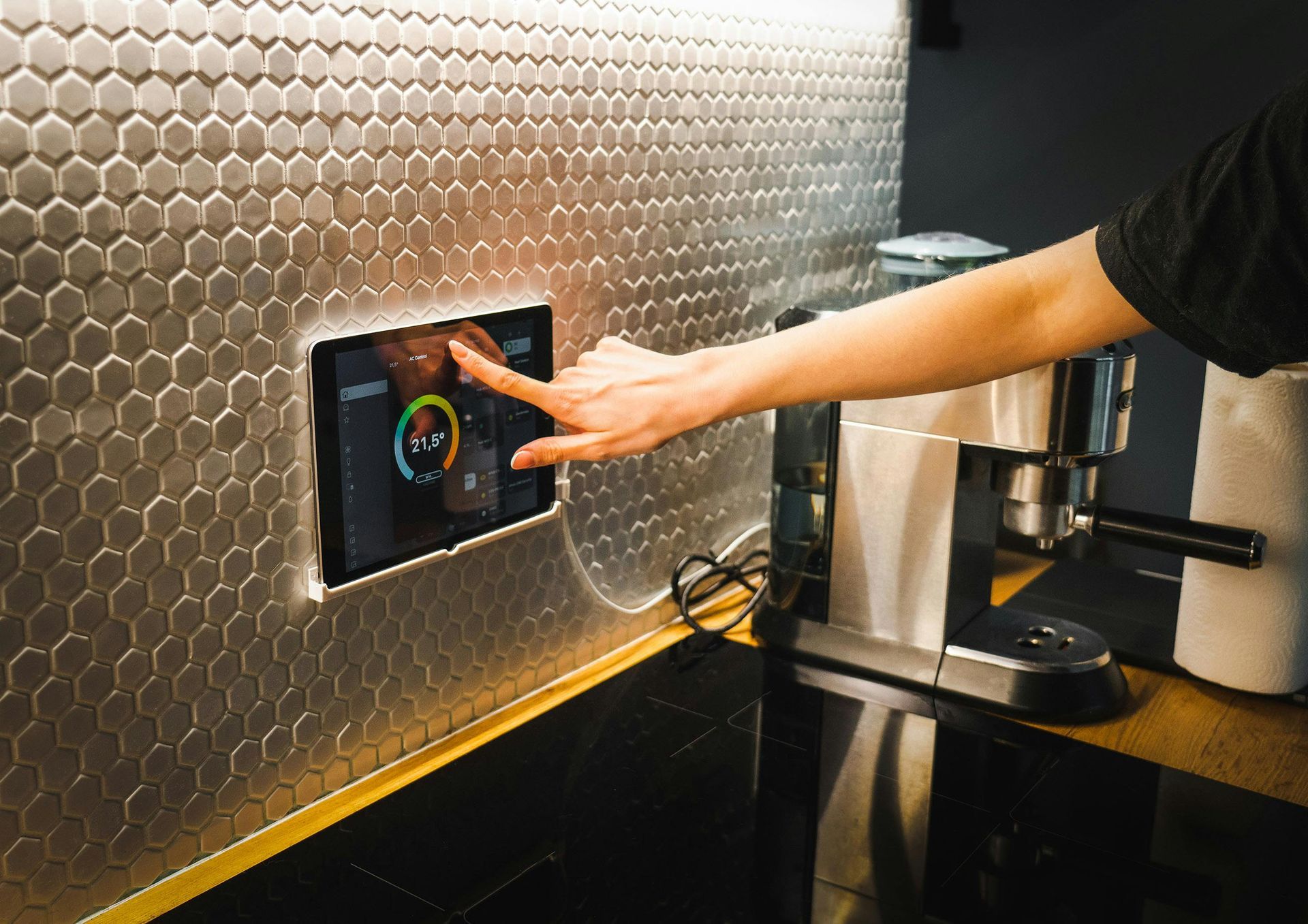 A person is pressing a button on a tablet in a kitchen.
