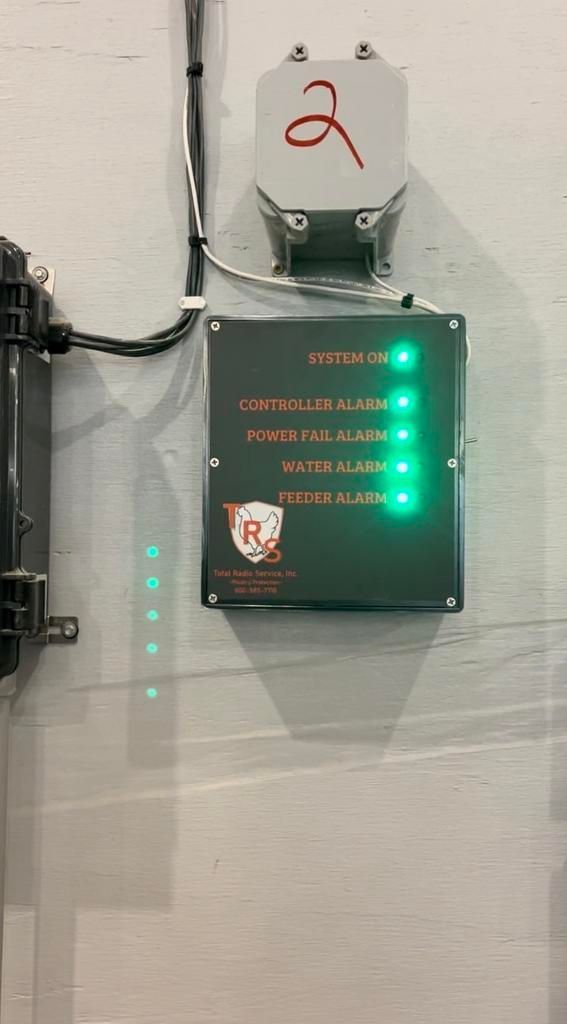 A box with a green light on it is hanging on a wall.