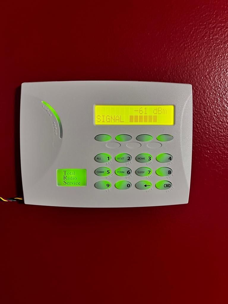 A security system is hanging on a red wall.