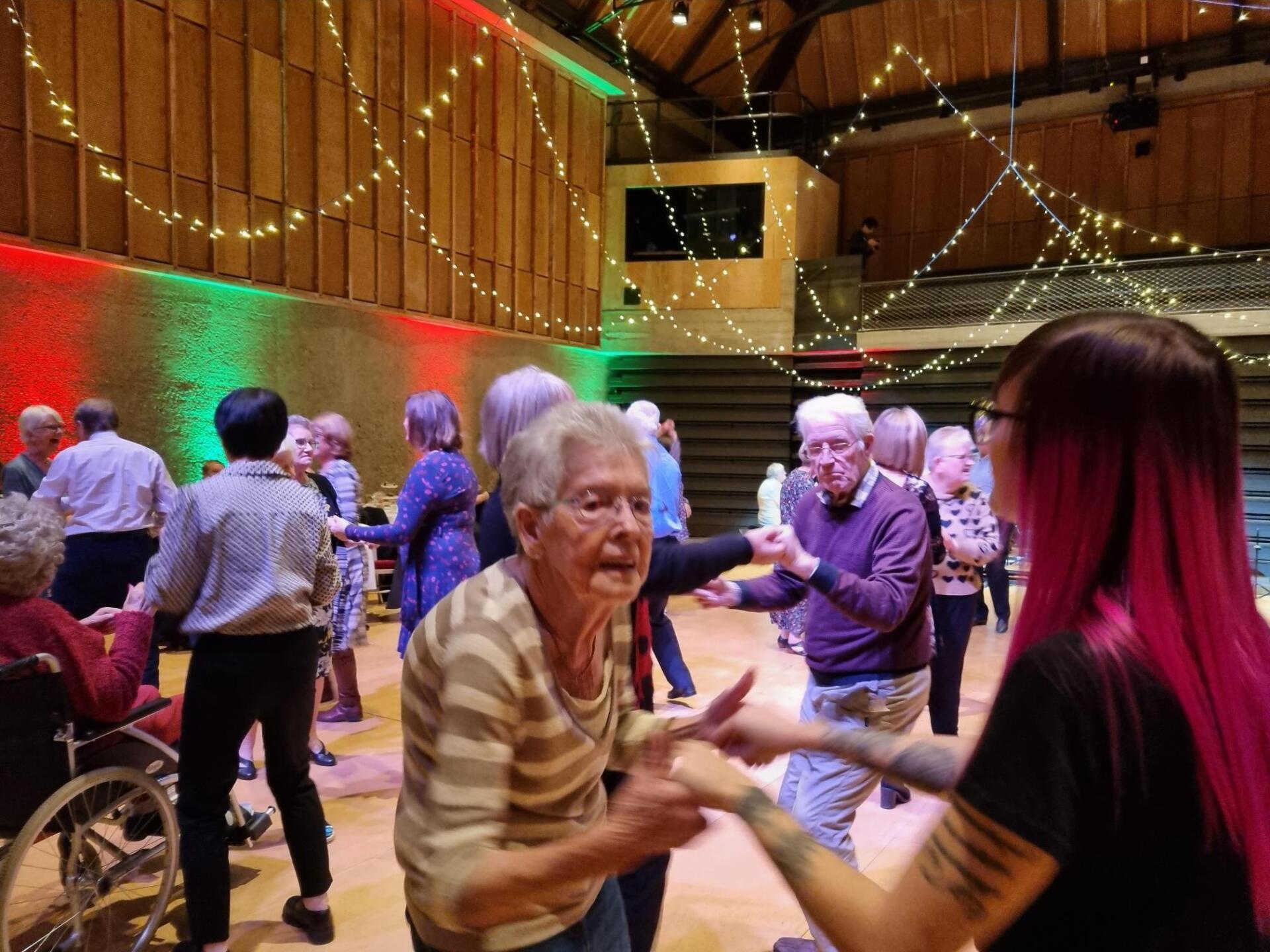 A woman with pink hair is dancing with a group of people