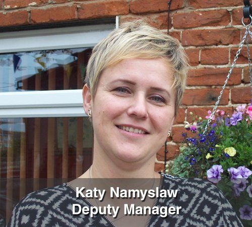 Katy namyslaw deputy manager is smiling in front of a brick building