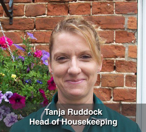 Tanja ruddock head of housekeeping is smiling in front of a brick wall