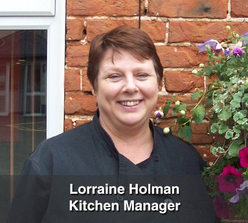Lorraine holman kitchen manager is smiling in front of a brick wall