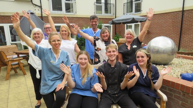 A group of people are posing for a picture with their hands in the air.