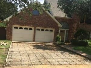 A residential brick house with a two-car garage and a driveway prepared with a wire mesh grid for a new concrete pour.