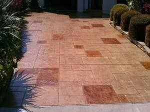Stamped concrete patio featuring a tan, multi-sized rectangular tile pattern with darker brown accent squares.