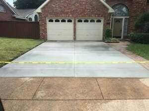 A residential driveway with a freshly poured concrete section separated from older pavement by yellow caution tape.