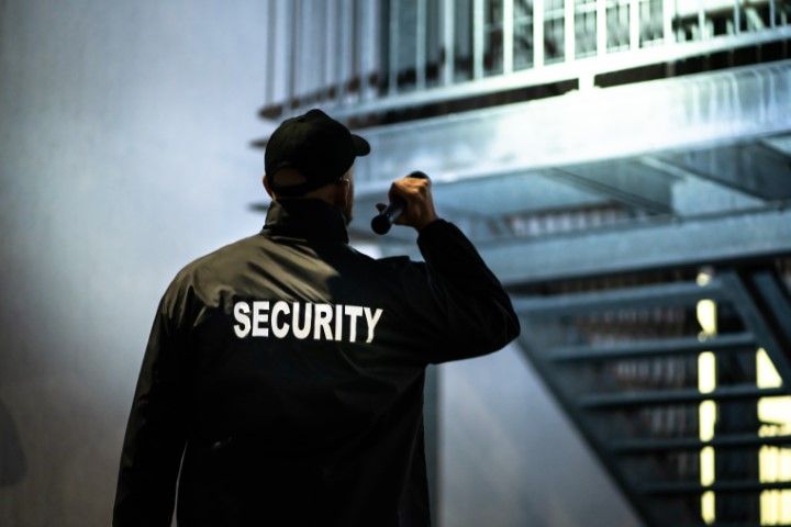 A security guard is holding a flashlight in front of a staircase.