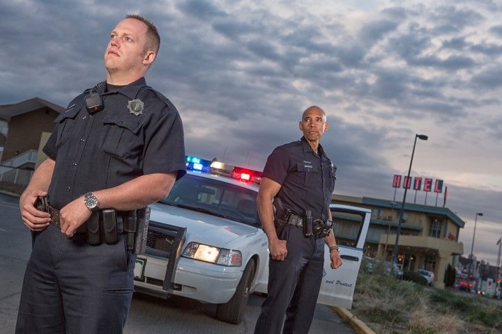 Two police officers are standing next to a police car.