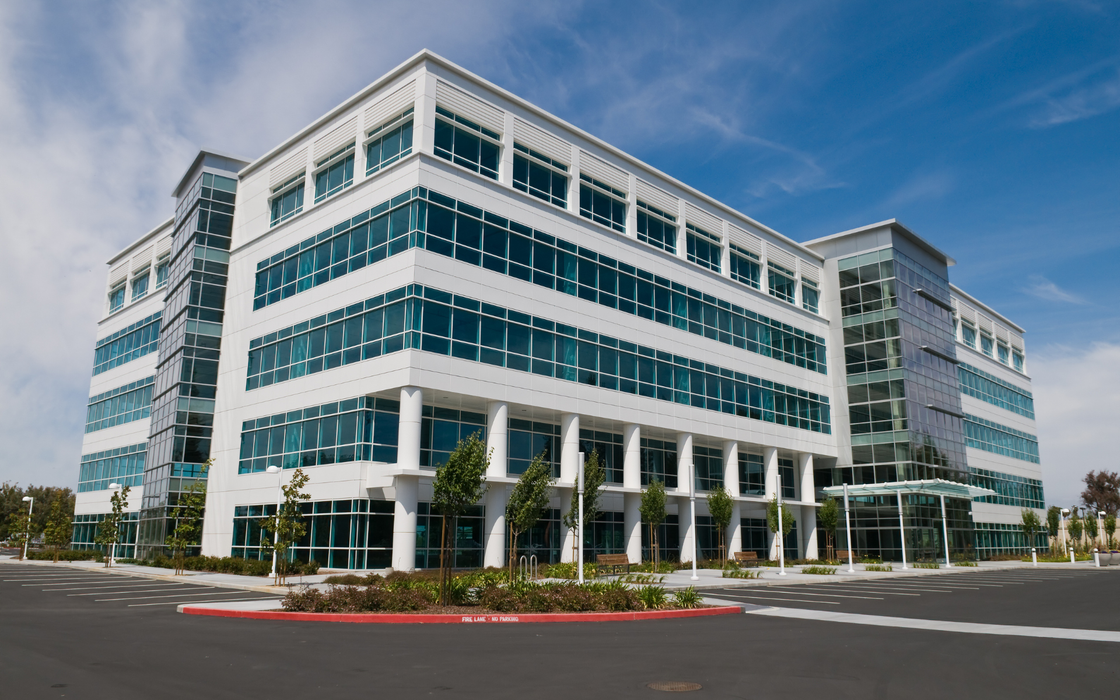 White and glass modern office building under a blue sky.