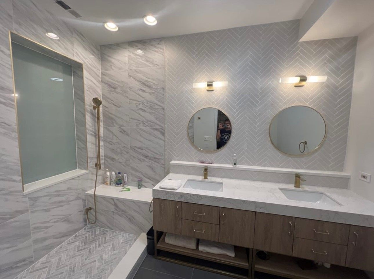 A bathroom with marble walls , a sink , and a large mirror.