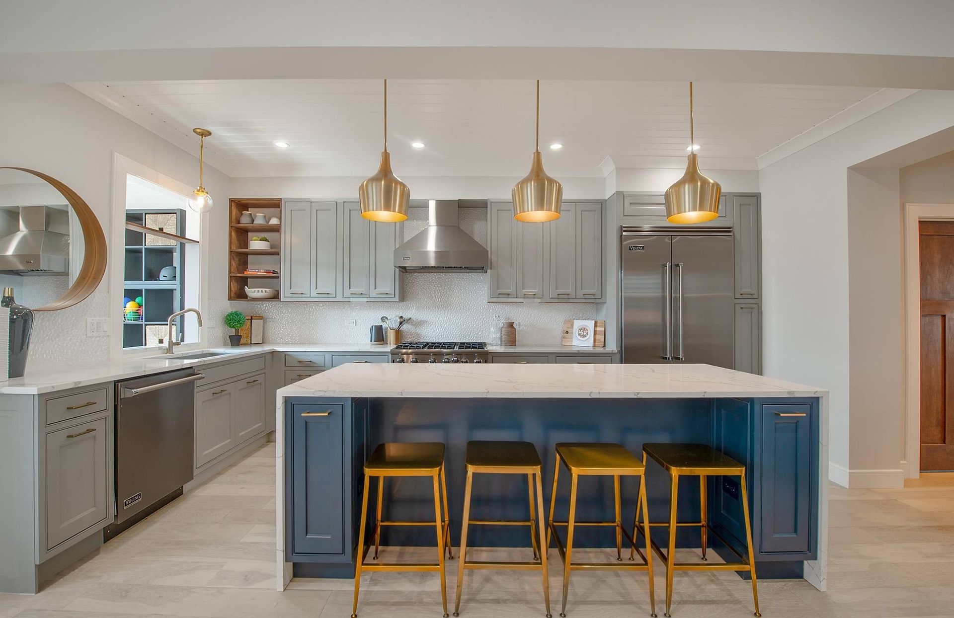 Modern kitchen with blue island, gold pendant lights, and stainless steel appliances