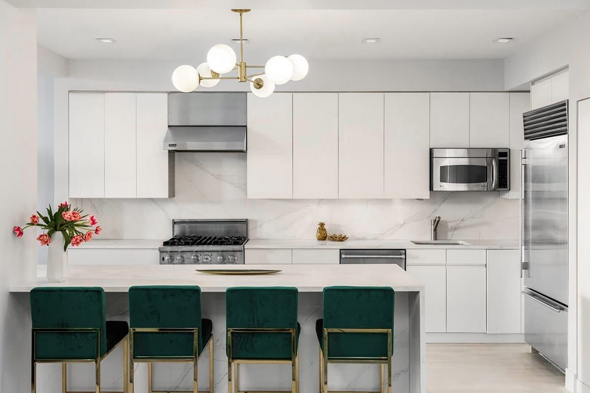 Bright white modern kitchen with teal barstools, marble island, and stainless steel appliances