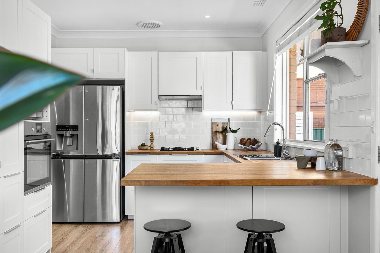 A kitchen with gray cabinets , white cabinets , stainless steel appliances and a large island.