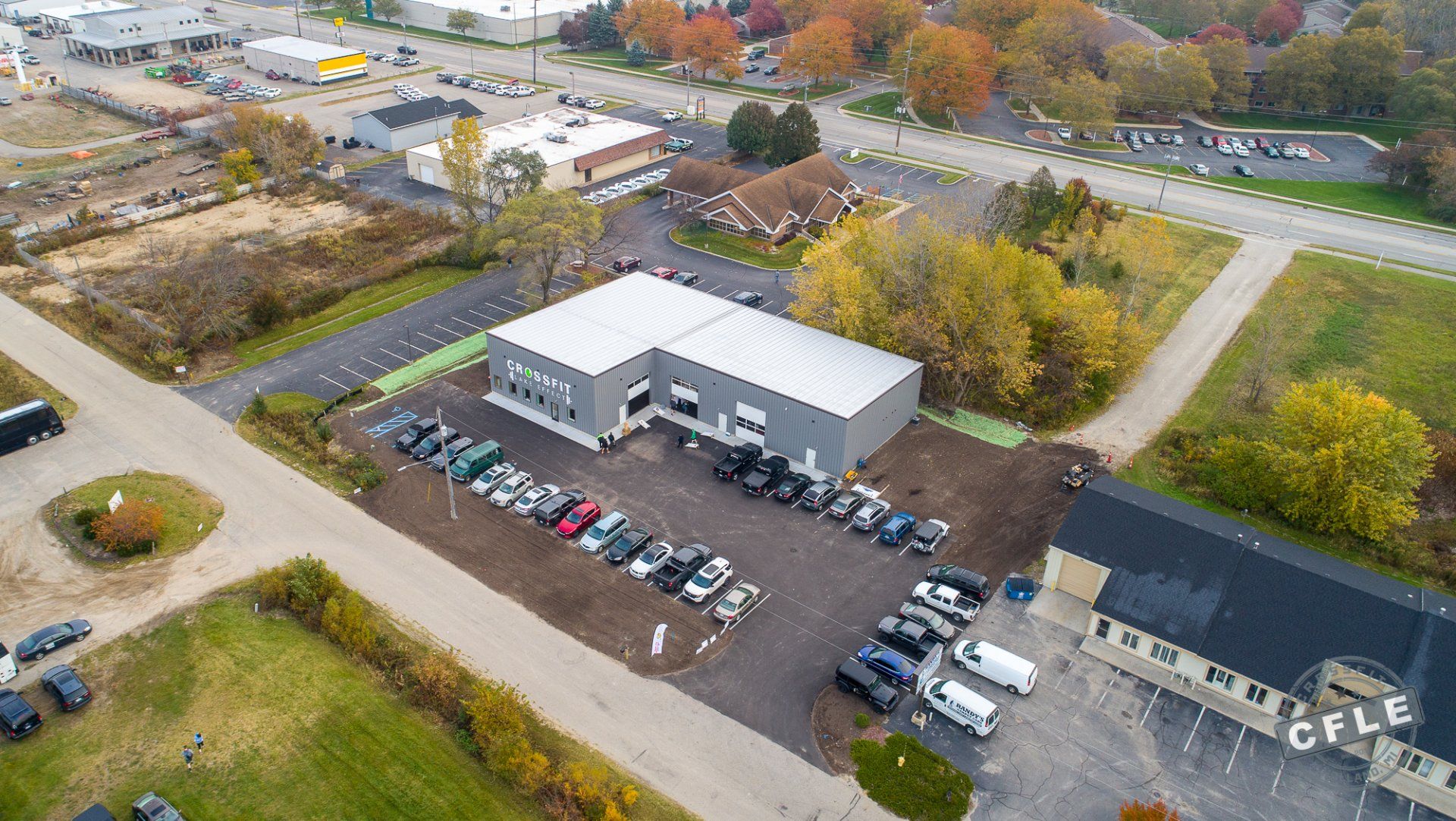 An aerial view of a parking lot with cars parked in front of a building.