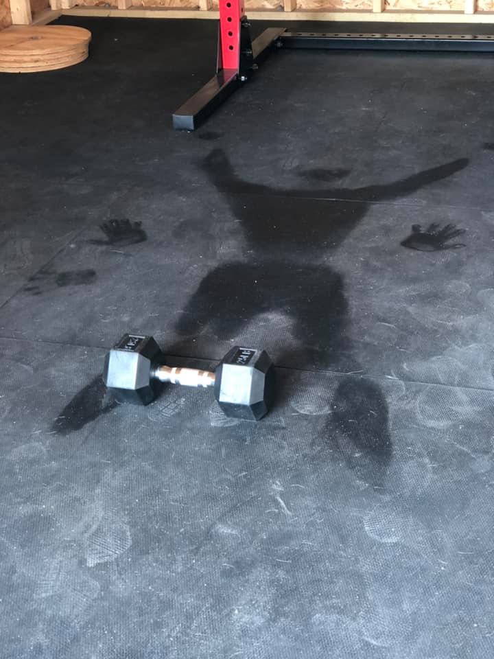 A pair of dumbbells are laying on the floor in a gym.