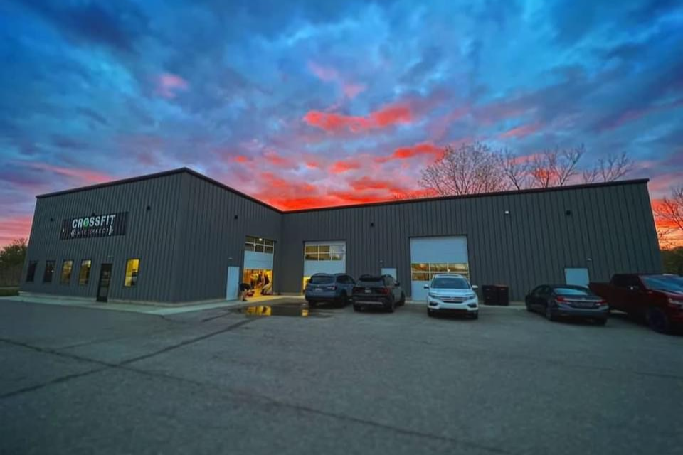 Crossfit Lake Effect building with cars parked in front of it at sunset.