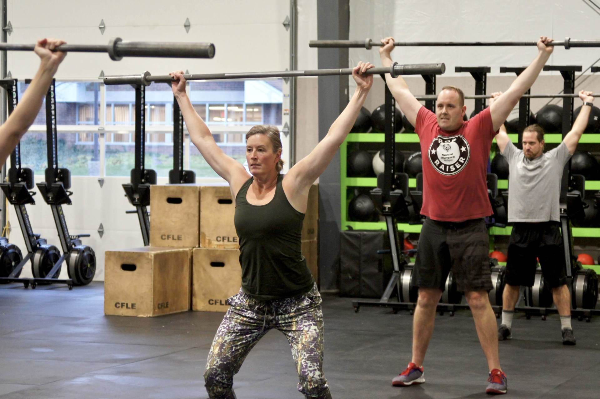 A group of people are lifting barbells in a gym.