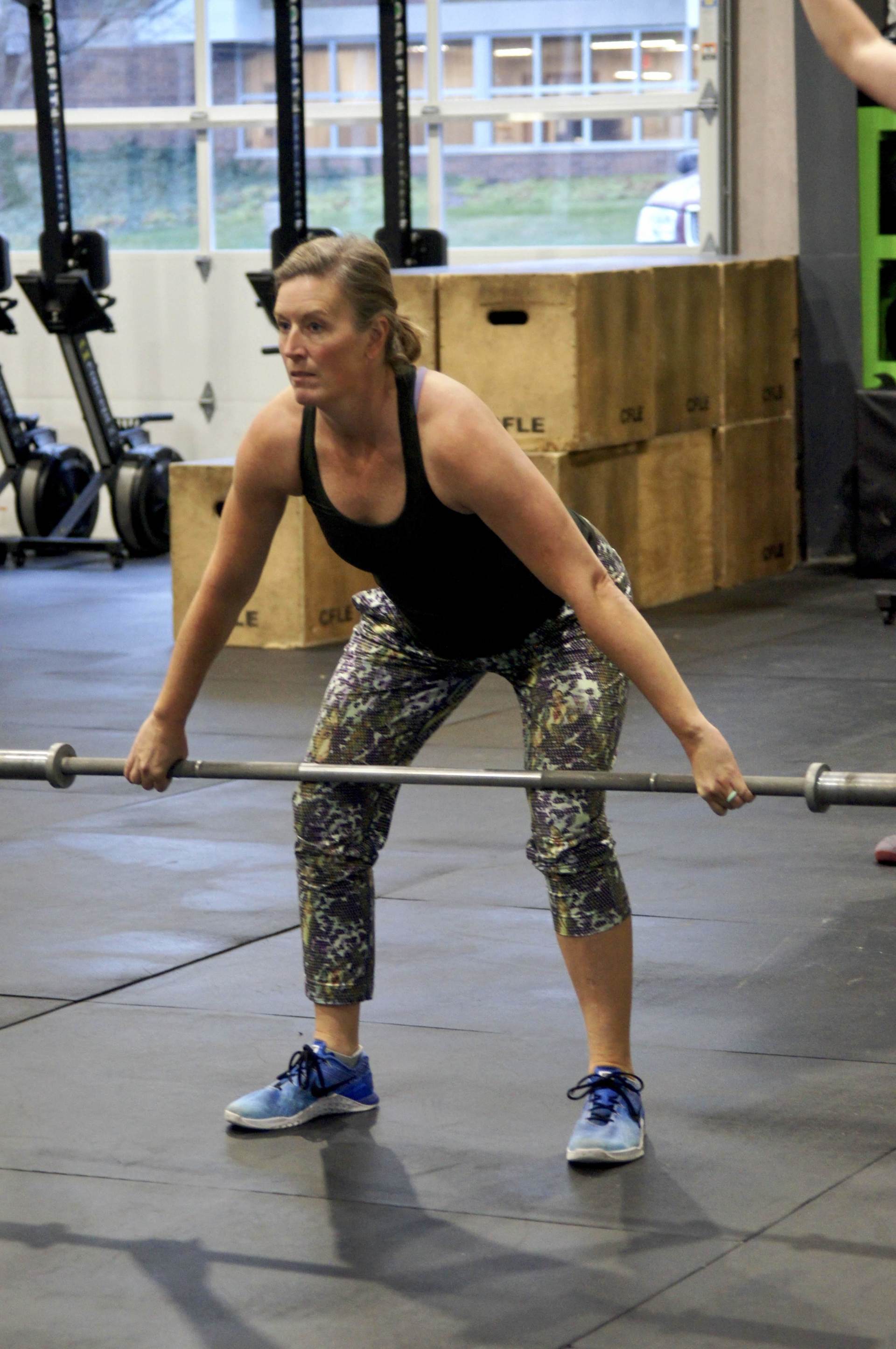 A woman is lifting a barbell in a gym