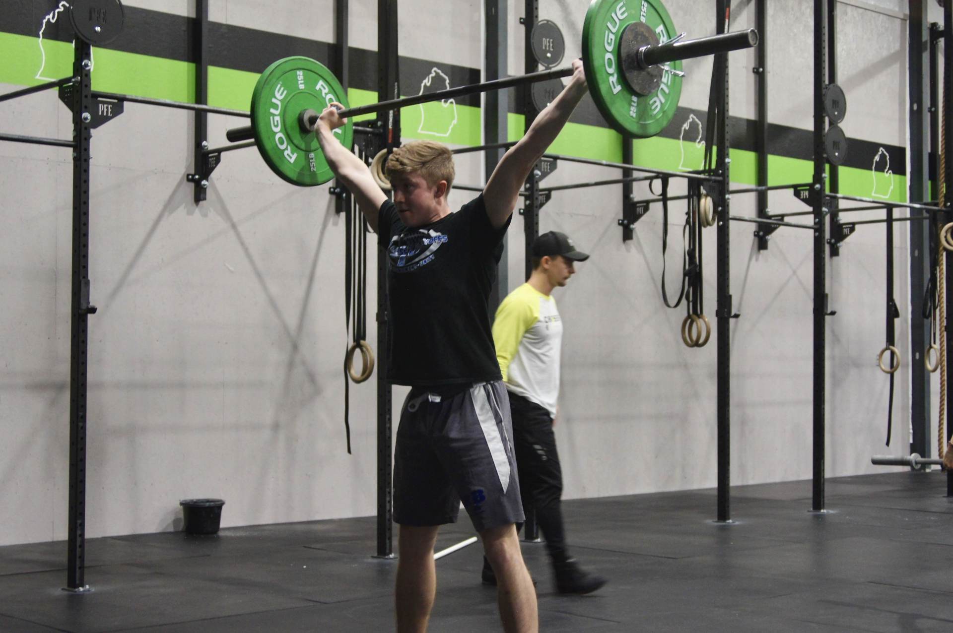 A man is holding a barbell over his head in a gym