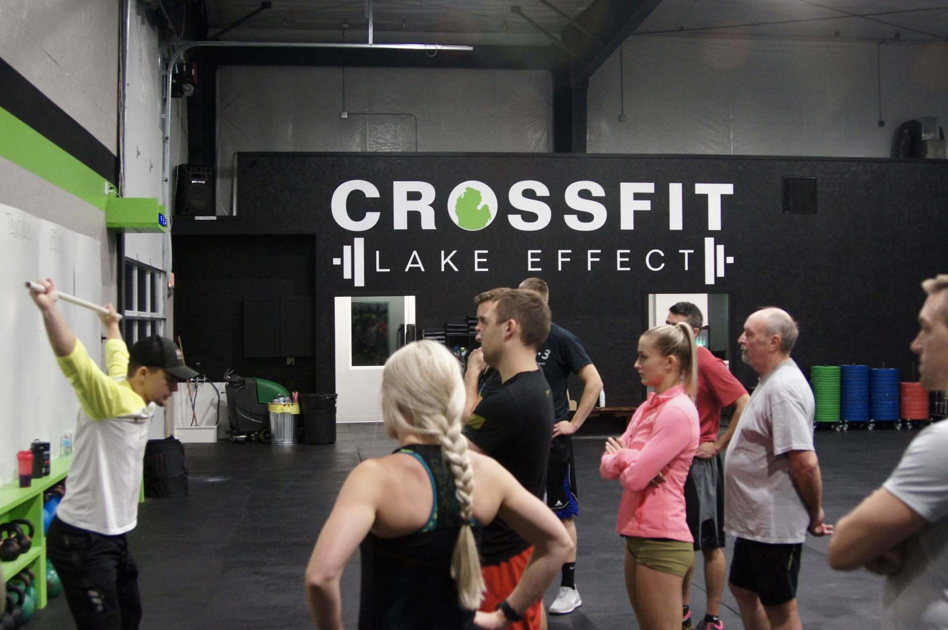 A group of people are standing in front of a wall that says crossfit lake effect.