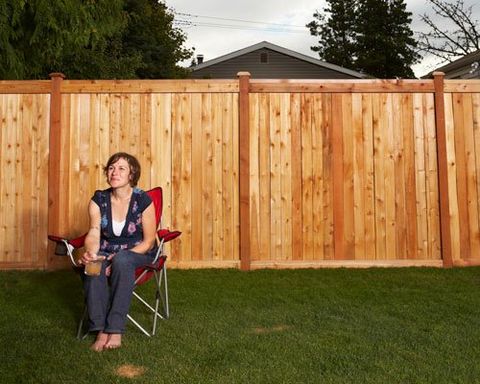 Woman sitting on chair in lawn by wooden fence - Estate Fence in Covington, WA