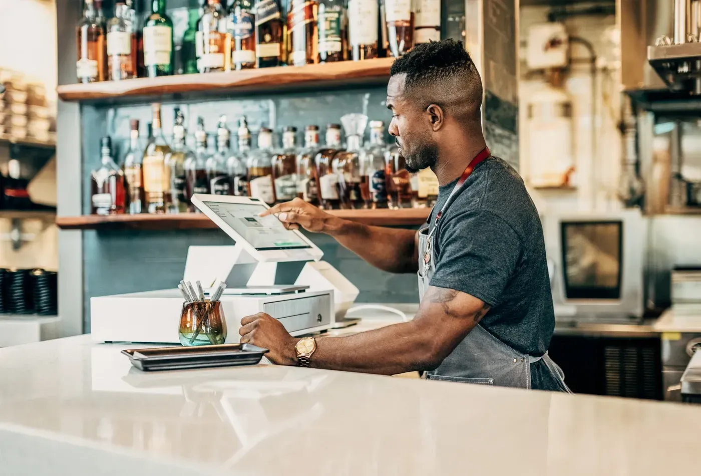 a man is sitting at a bar using a Clover POS Station .