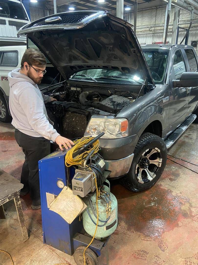 A man is working on a truck in a garage with the hood open | Cetus Automotive Repair Centre