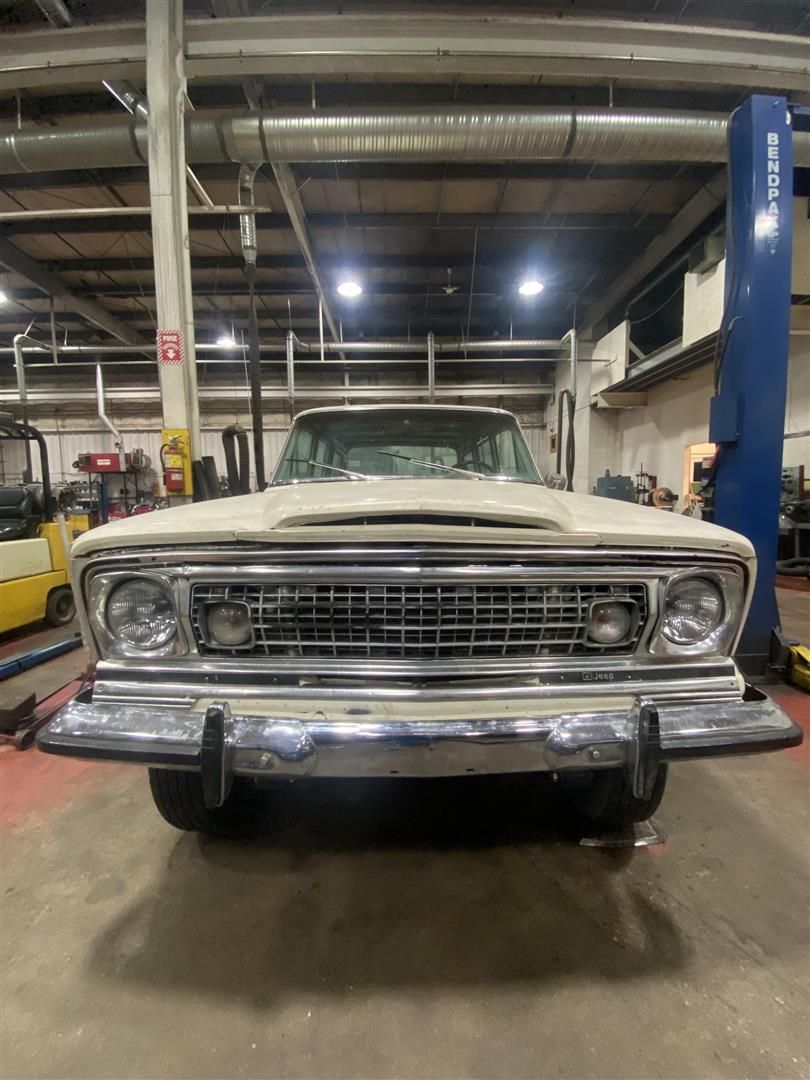 A white jeep is parked in a garage on a lift | Cetus Automotive Repair Centre