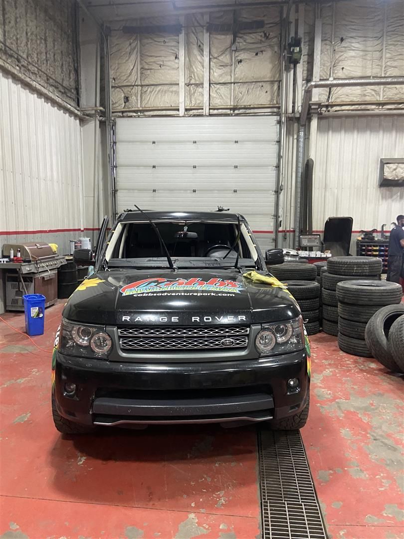 A black range rover sport is parked in a garage next to a bunch of tires| Cetus Automotive Repair Centre