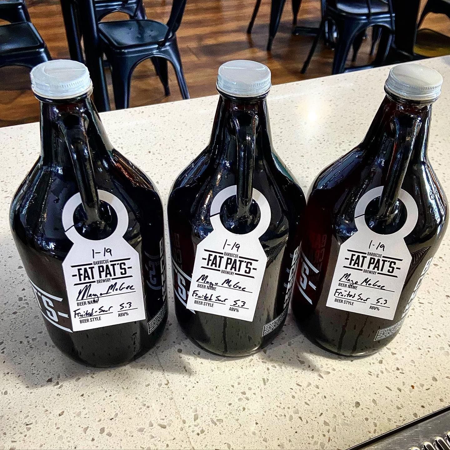 Three bottles of beer are sitting on a counter.